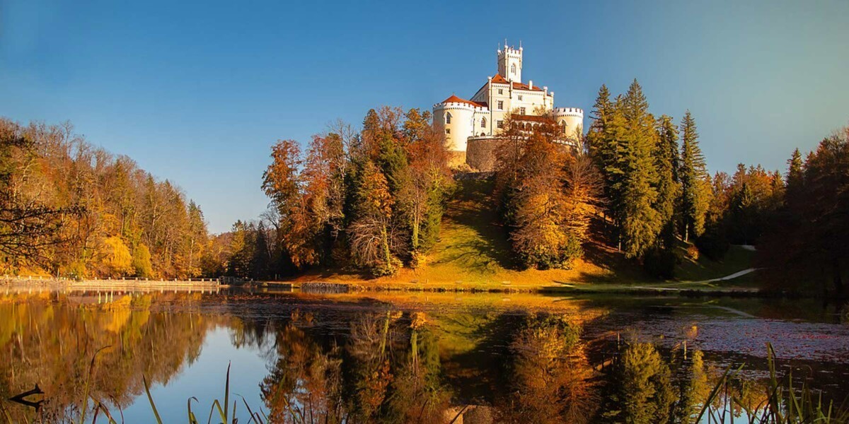 Trakošćan Castle above the lake, surrounded by autumn woodland in northern Croatia.